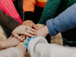 person in red sweater holding babys hand